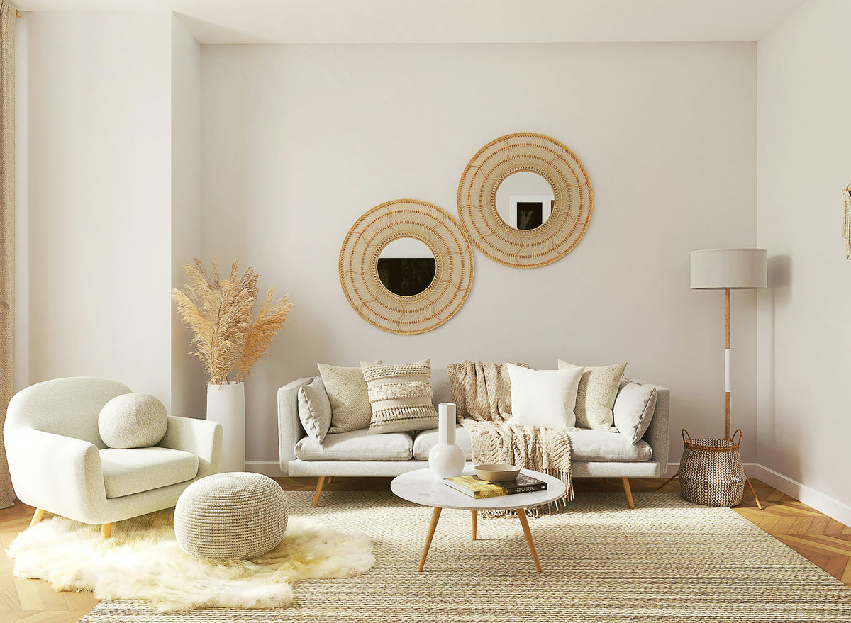 Neutral-toned living room with a cream sofa, boucle armchair, woven wall mirrors, textured cushions, round coffee table and natural fibre rug.