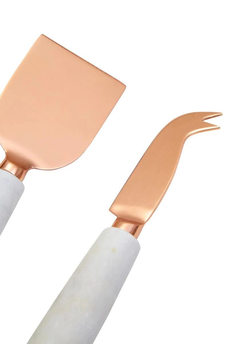 The flat and forked cheese knives from the Loxley set, with copper-finish blades and white marble handles.