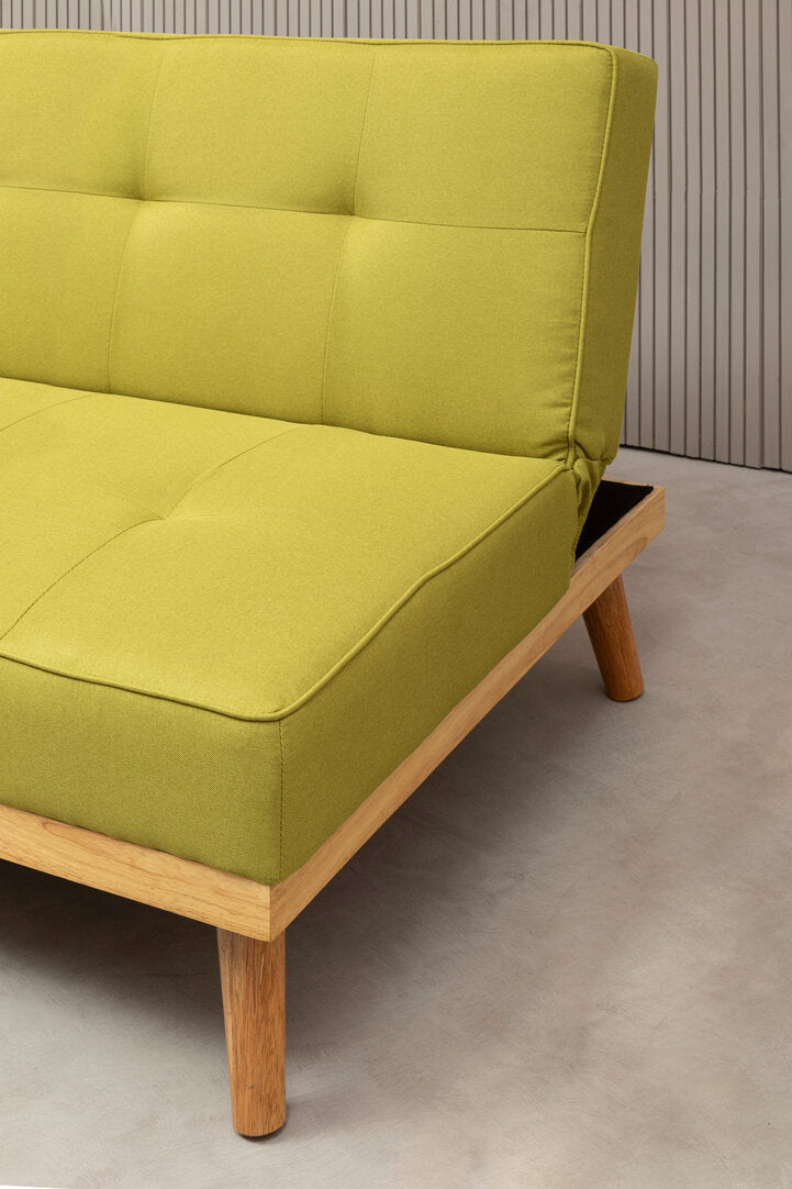 Close up of the side of a lime green fabric sofa bed with wooden legs on a neutral floor
