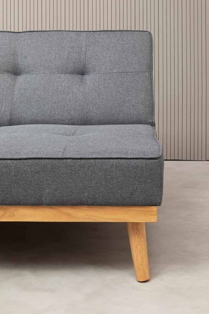 Gray fabric sofa with wooden legs against a neutral wall.