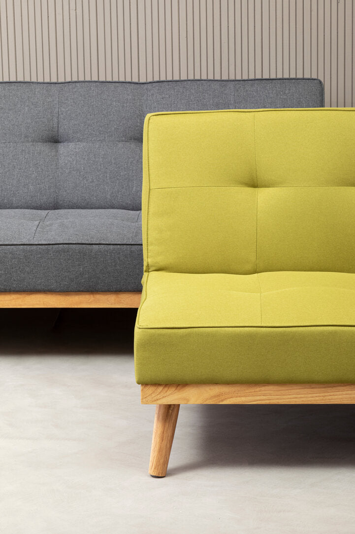 Two couches, one gray and one green, against a neutral wall.