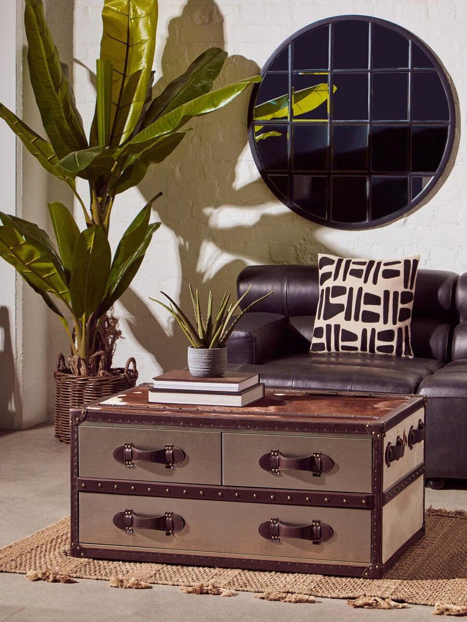 Living room with a leather sofa, decorative pillow, and a vintage-style trunk table.