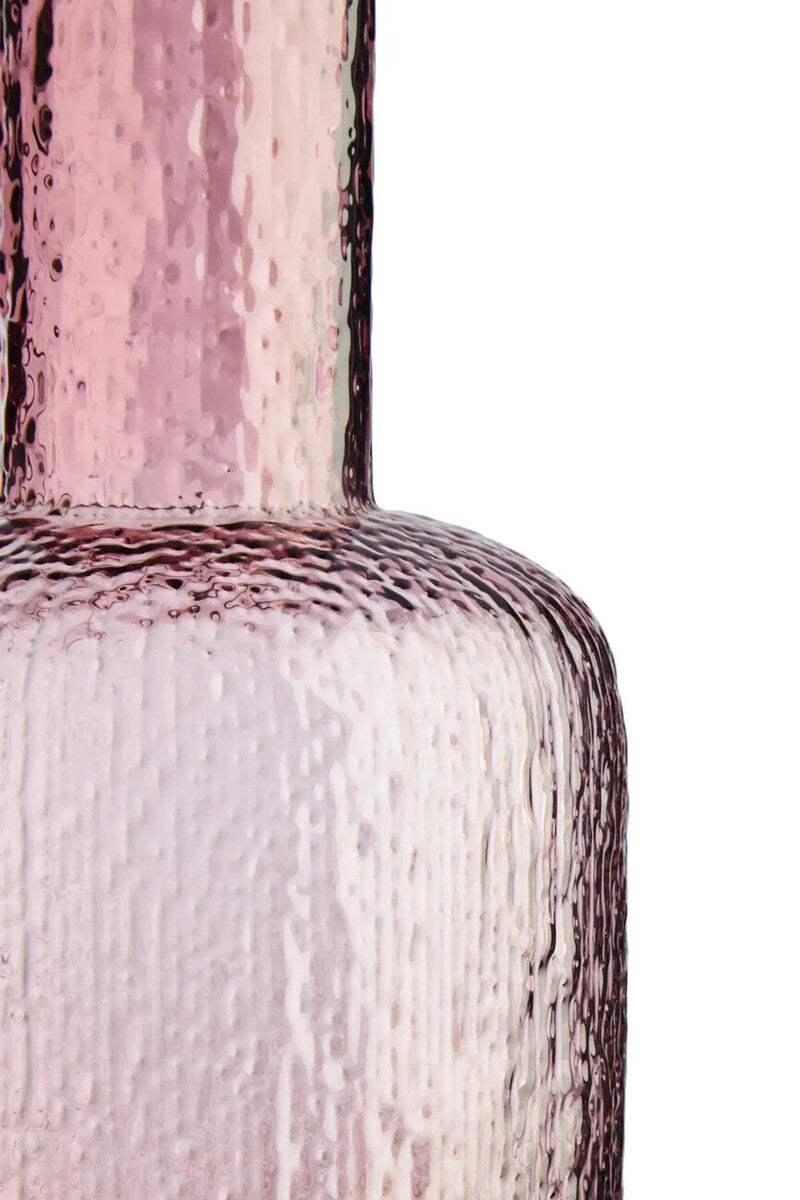 Close-up of a textured pink glass bottle on a white background