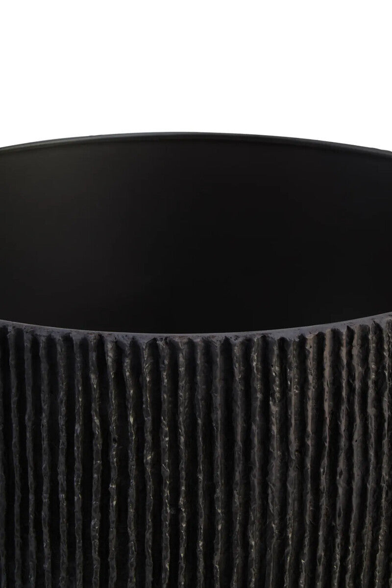 The shade of a black ribbed table lamp on a white background