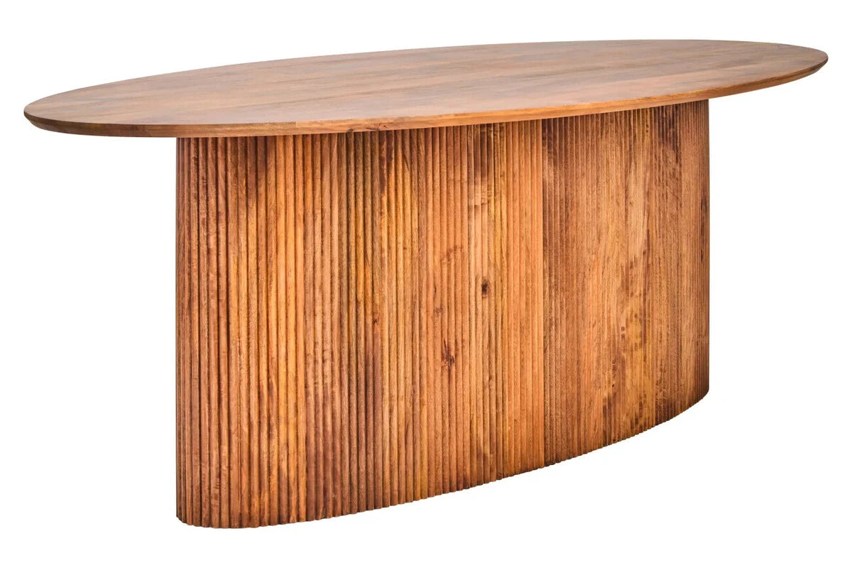The Hawthorn Mango Wood Oval Dining Table from a three-quarter angle, showing the oval top and fluted mango wood pedestal.