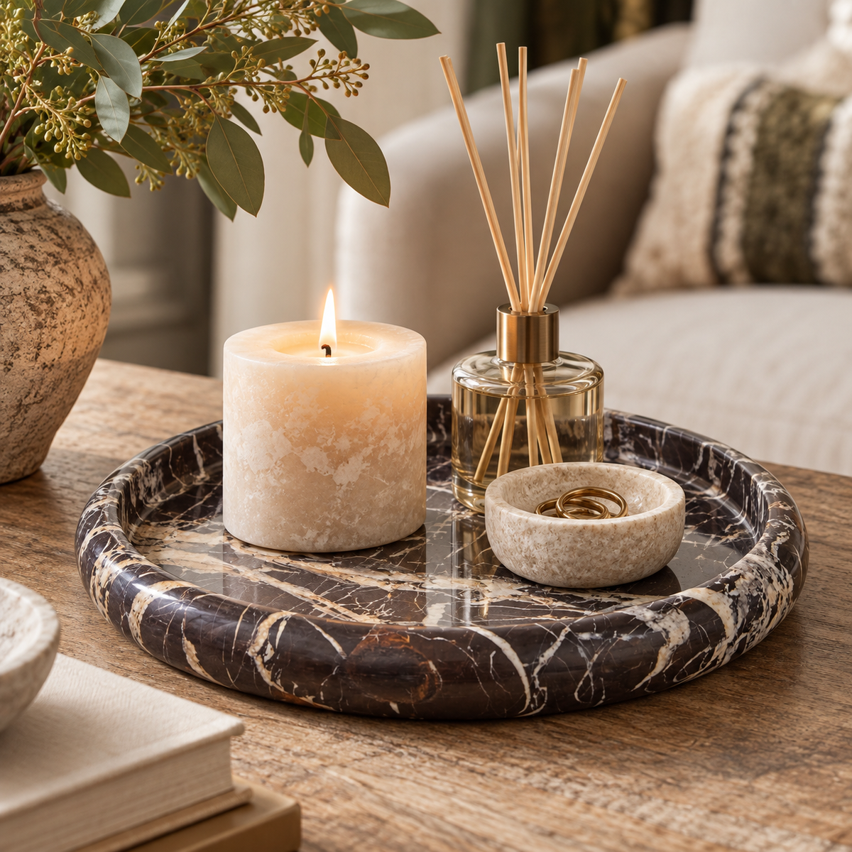Alba Black and White Marble Round Tray styled on a rustic wooden table with a candle, reed diffuser and small decorative bowl.