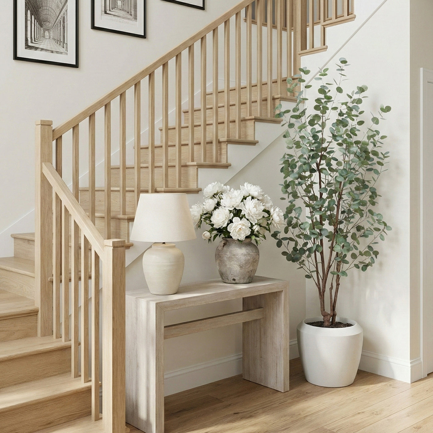 Staircase with wooden railings, a small table with a lamp and flowers, and a eucalyptus tree in a home interior.
