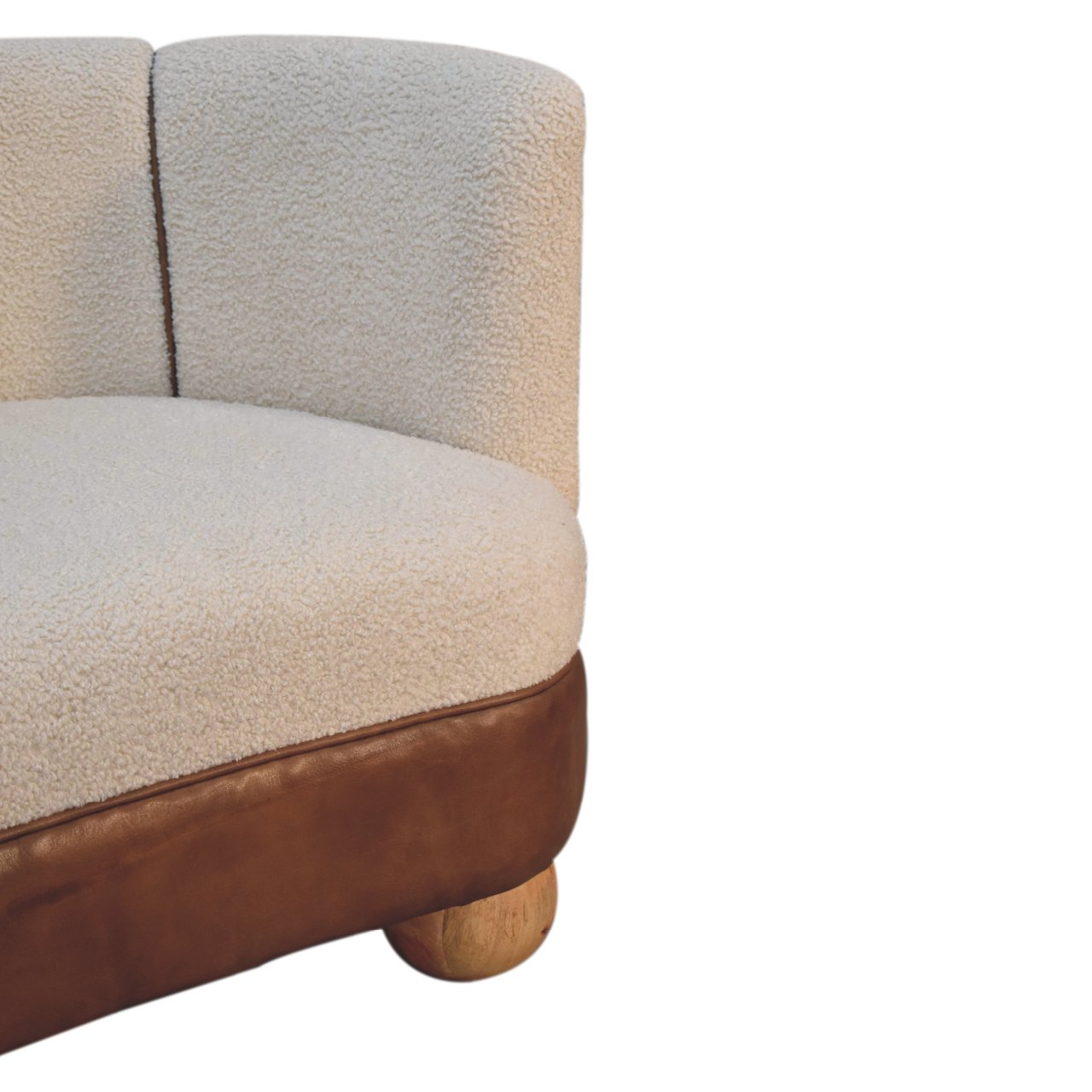 A view of the arm of a cream boucle sofa with buffalo leather detail