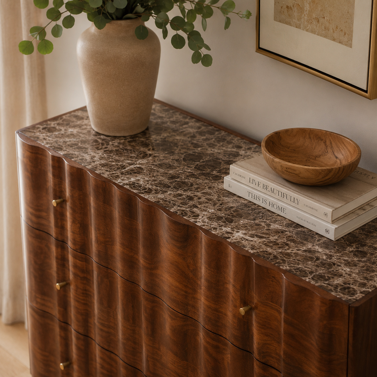 Wooden chest of drawers with marble top, vase, and books in a home setting
