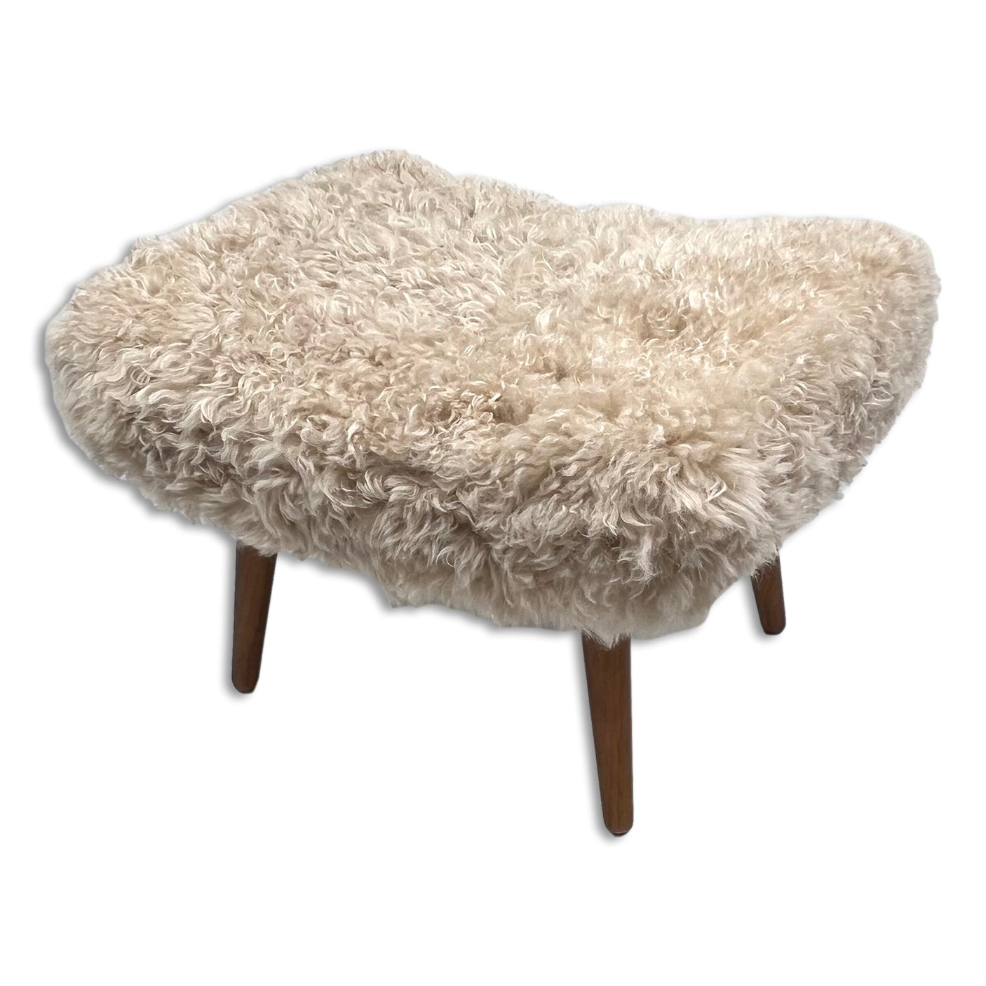 Beige shearling sheepskin footstool with wooden legs on a white background