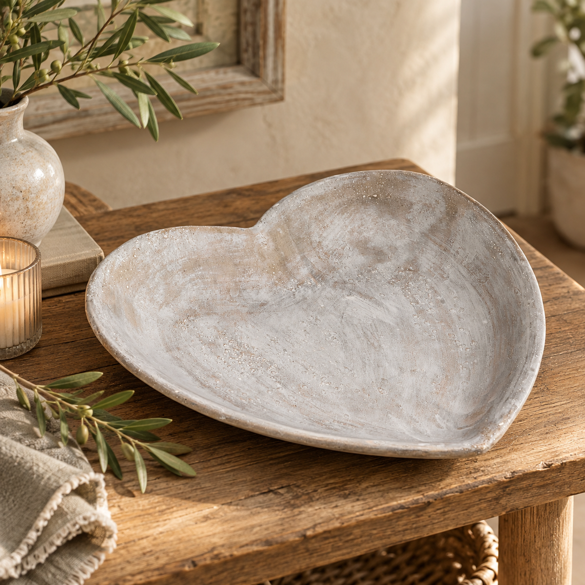 Stone Heart Dish on a wooden table beside olive branches, a lit candle and a linen napkin