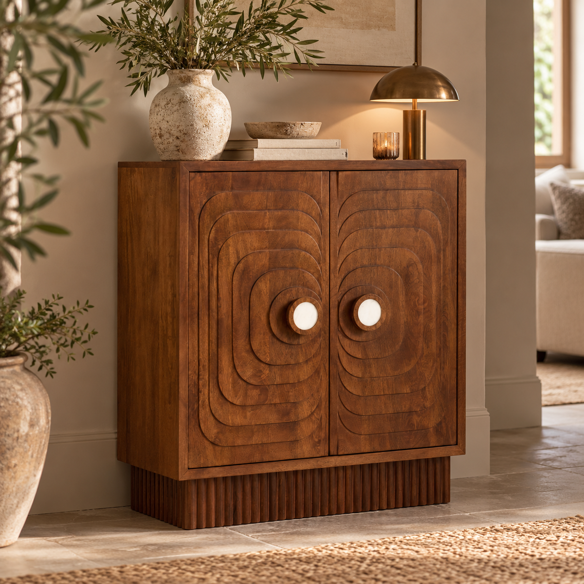 A mid-century modern wooden sideboard cabinet with two doors featuring concentric oval carved patterns and round knobs, styled in a warm, neutral-toned living room setting.