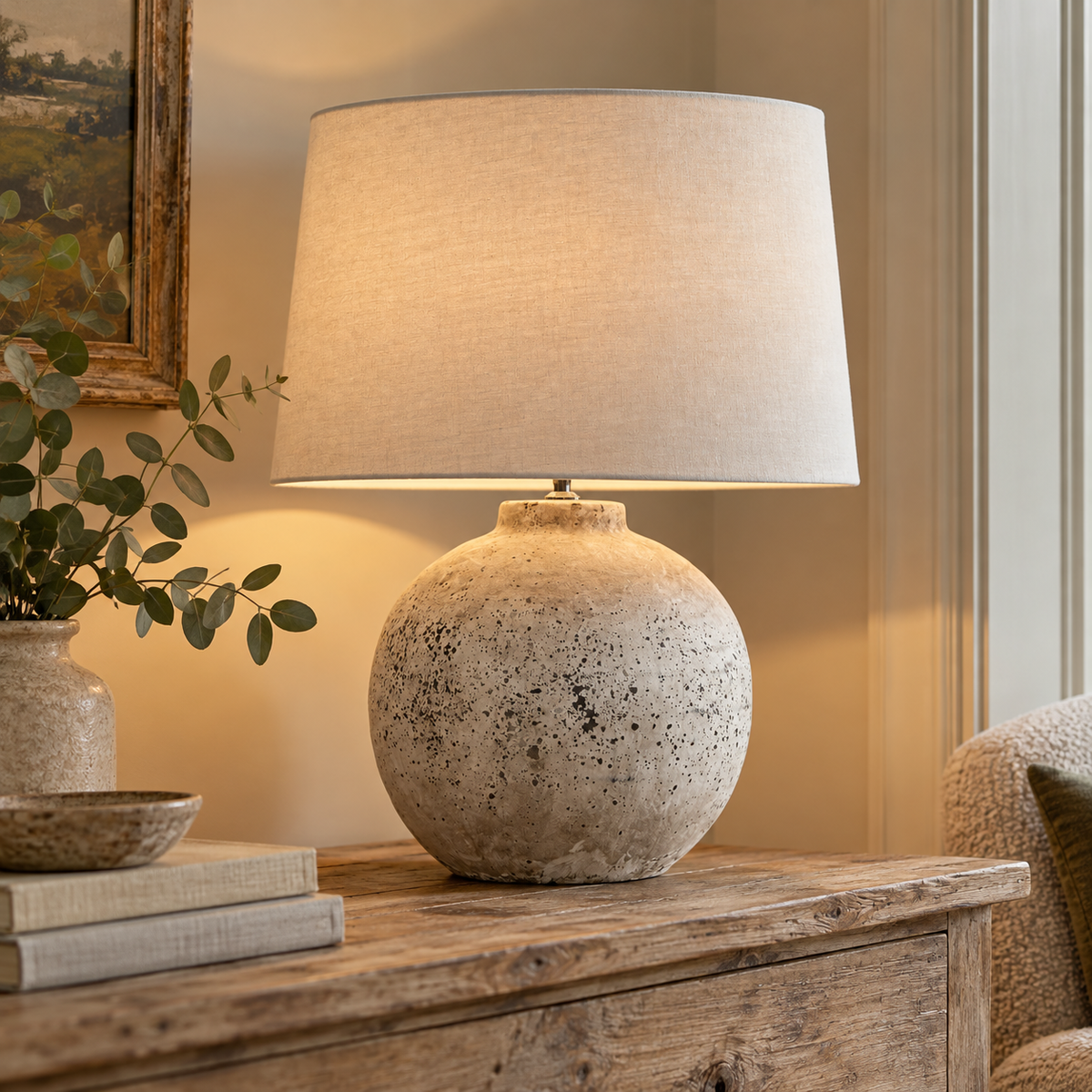 Tiber Large Stone Ceramic Table Lamp lit on a rustic wooden console beside olive branches and books