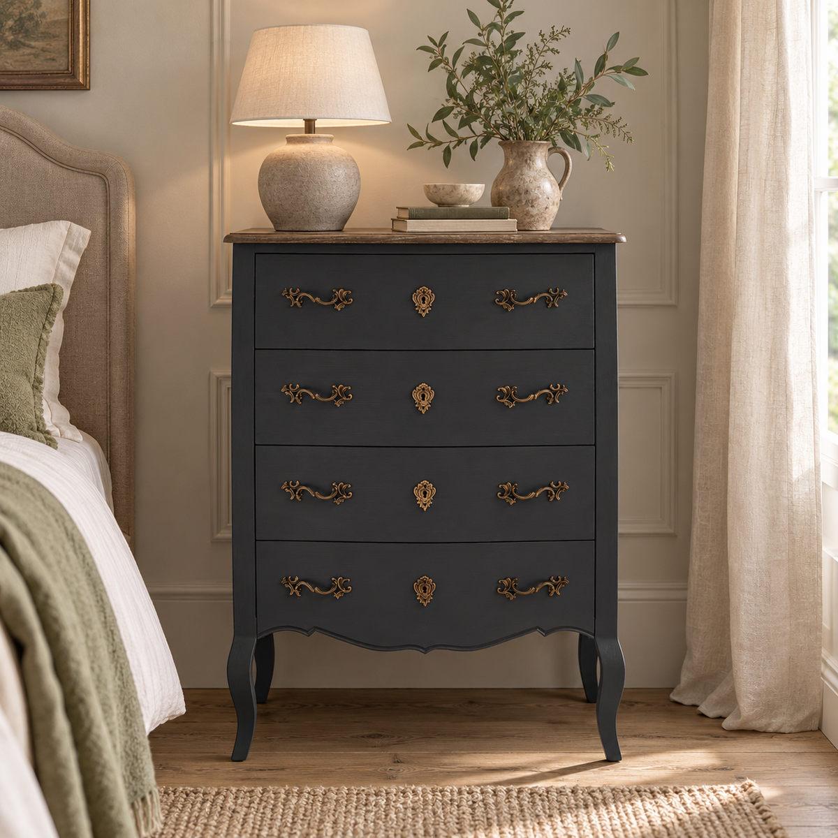 Vienne 4 Drawer Dark Grey Chest of Drawers in a bedroom, styled with a ceramic table lamp, a jug of greenery and books