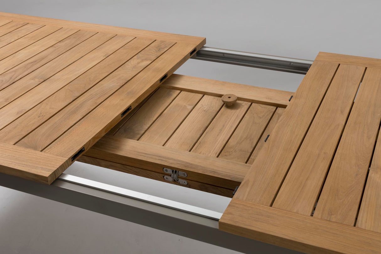 Close-up of a wooden table extension with slatted panels and metal rails, shown in a clean studio-style setting.
