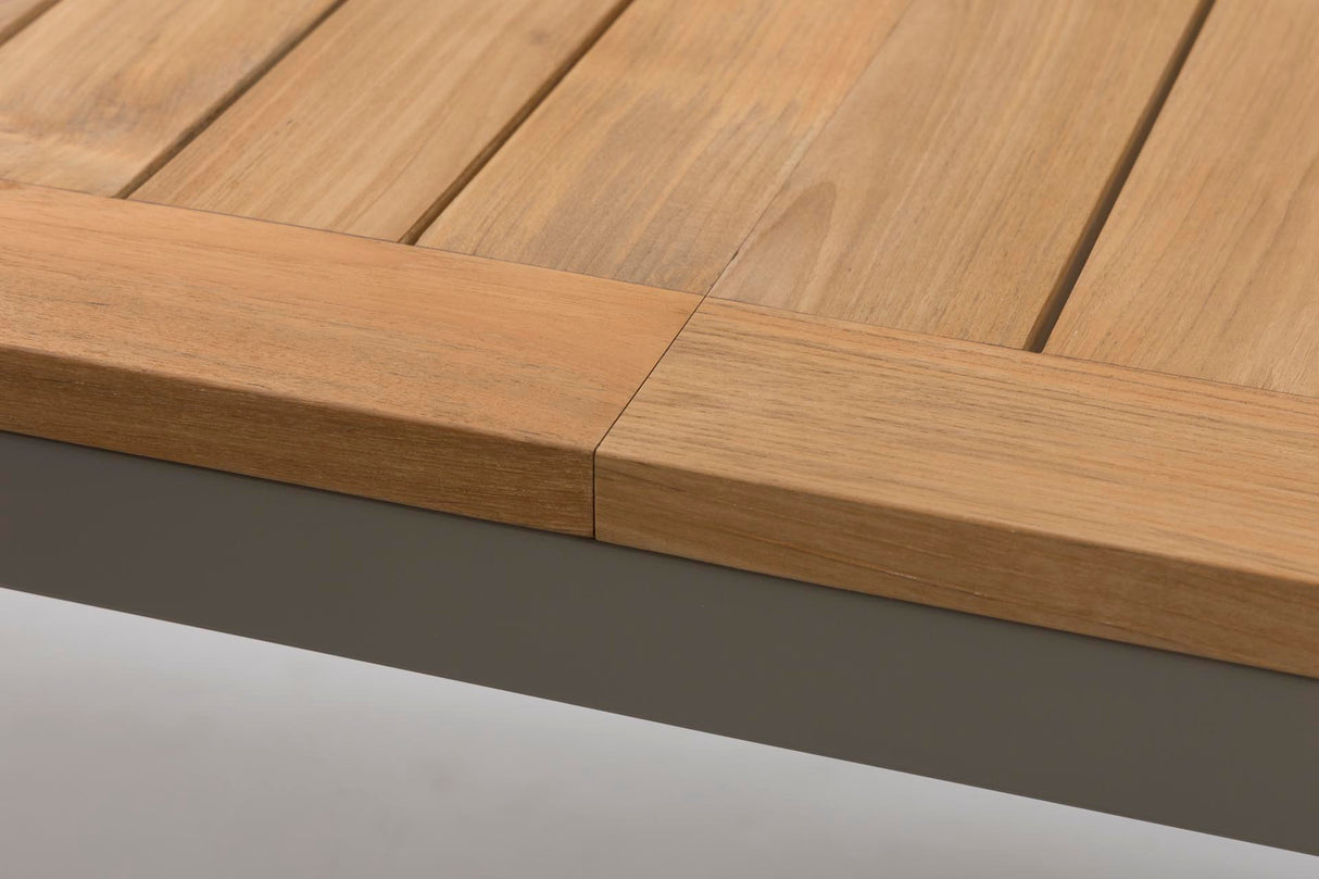 Close-up of a wooden slatted tabletop with a thick natural wood apron and edge, shown against a light gray background.