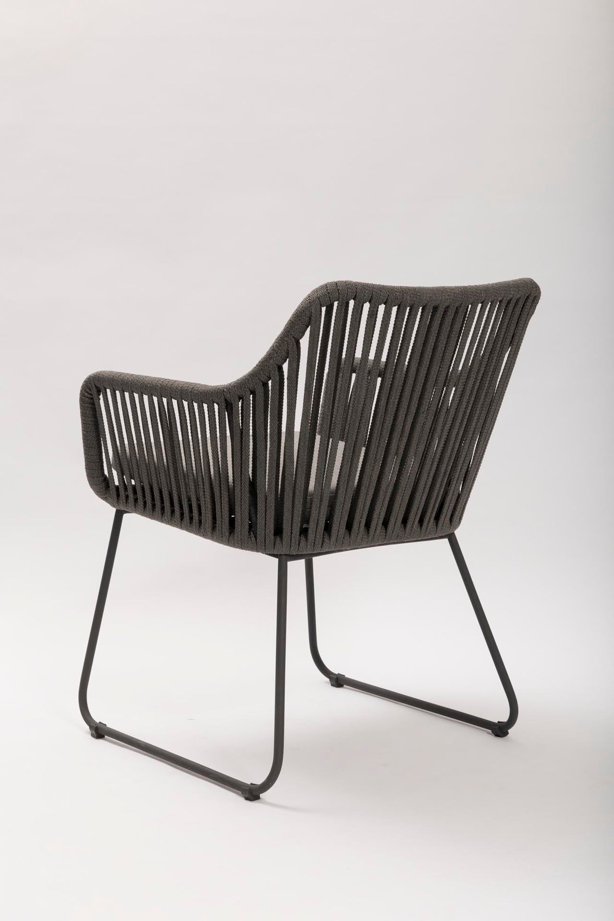 Rear view of a dark grey outdoor dining chair on a white background