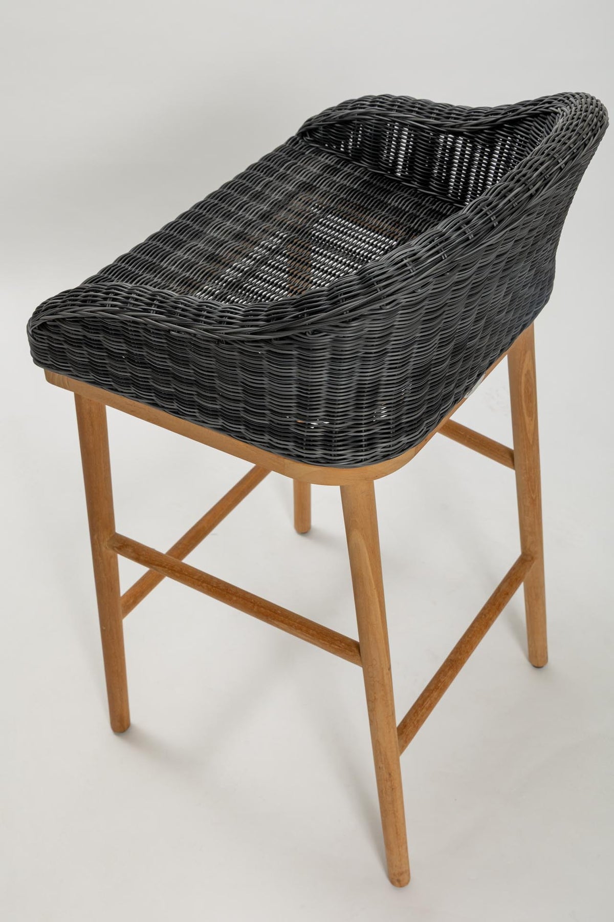 Bar stool with woven dark grey seat and wooden legs on a white background