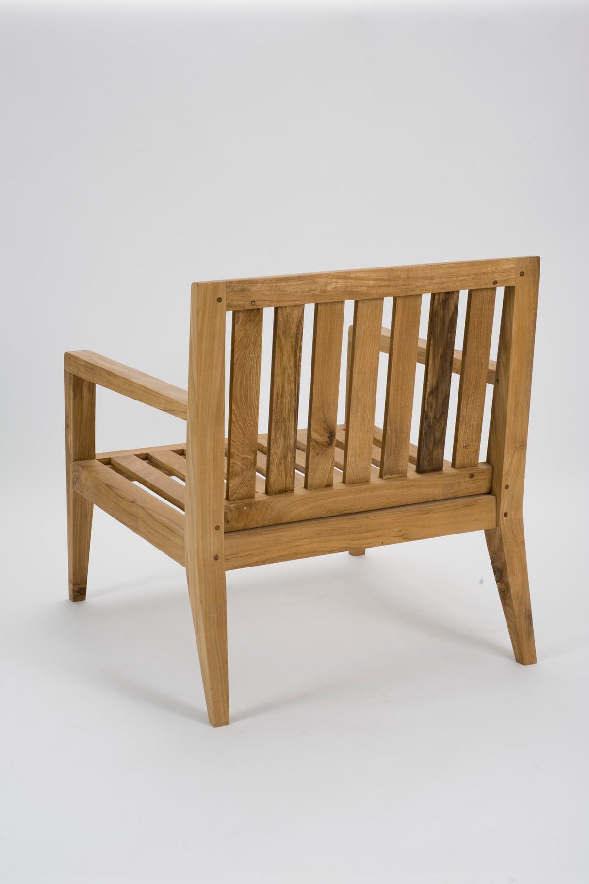 A light natural wood armchair with a slatted backrest and seat, shown from a three-quarters angle against a plain white studio background.