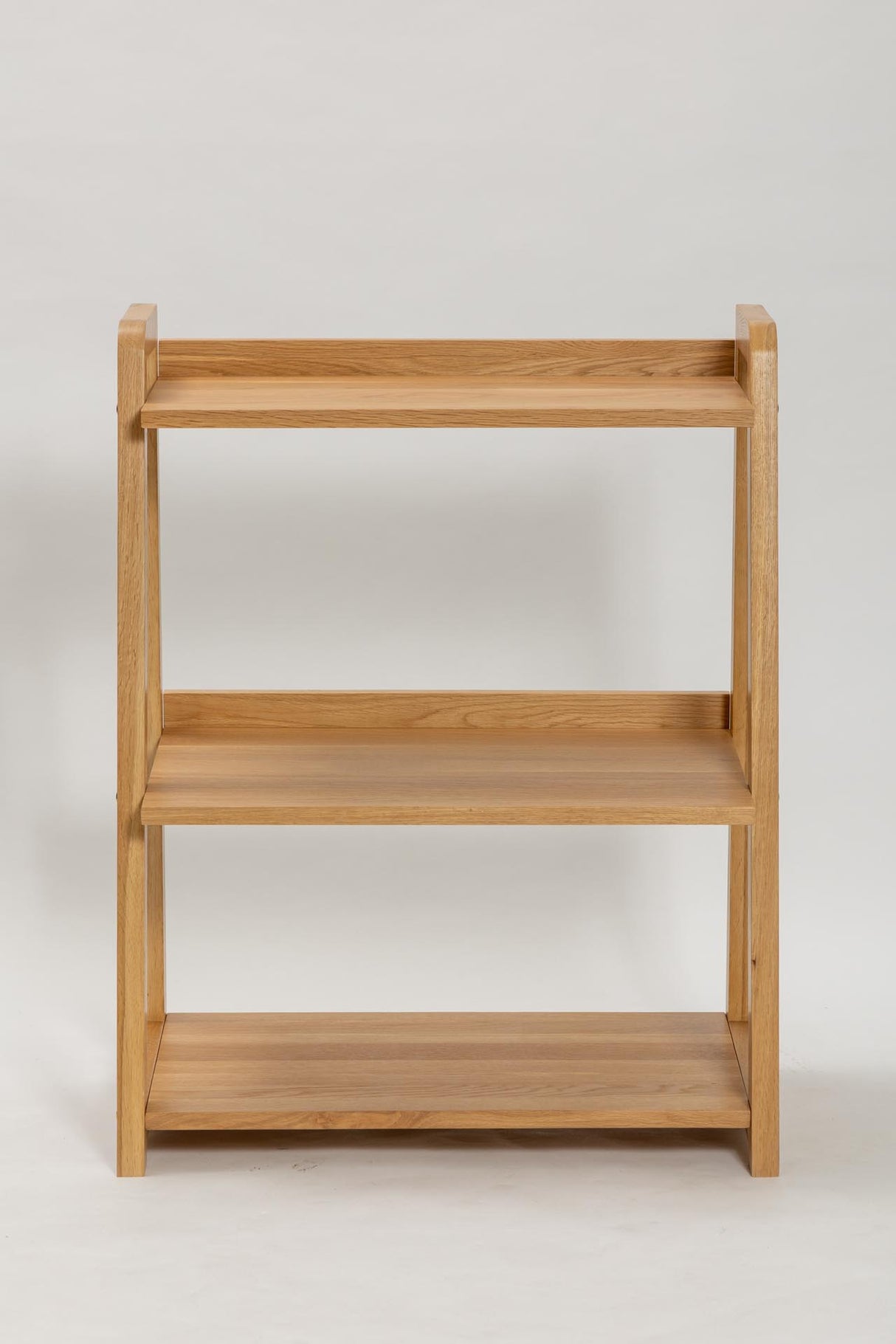 A three-tier wooden bookshelf with a natural oak finish, shown against a plain light gray background.
