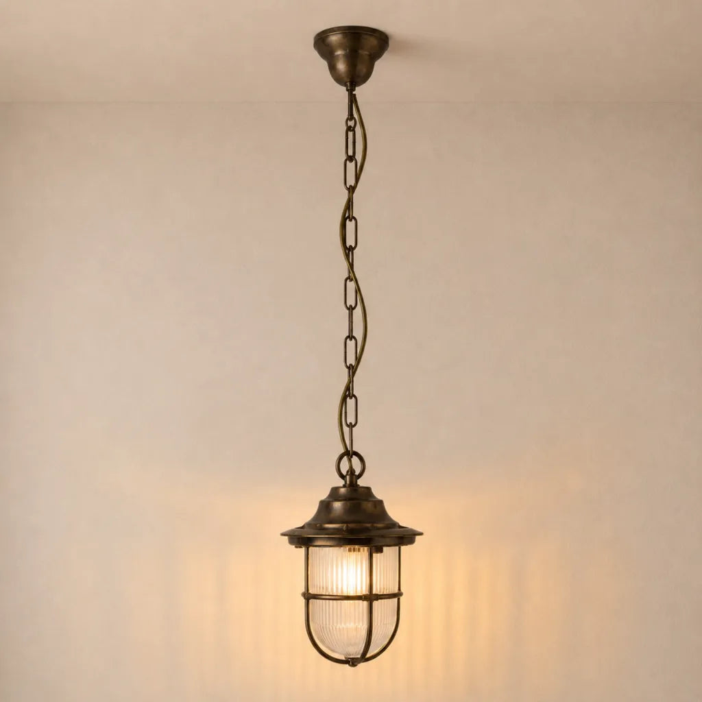 Bronze pendant light with clear glass shade on a neutral background