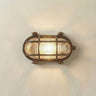 A vintage-style nautical wall sconce with a bronze-finished metal frame and ribbed clear glass panels, illuminated against a plain off-white wall.