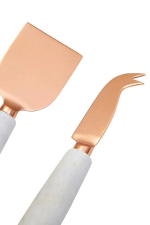 The flat and forked cheese knives from the Loxley set, with copper-finish blades and white marble handles.
