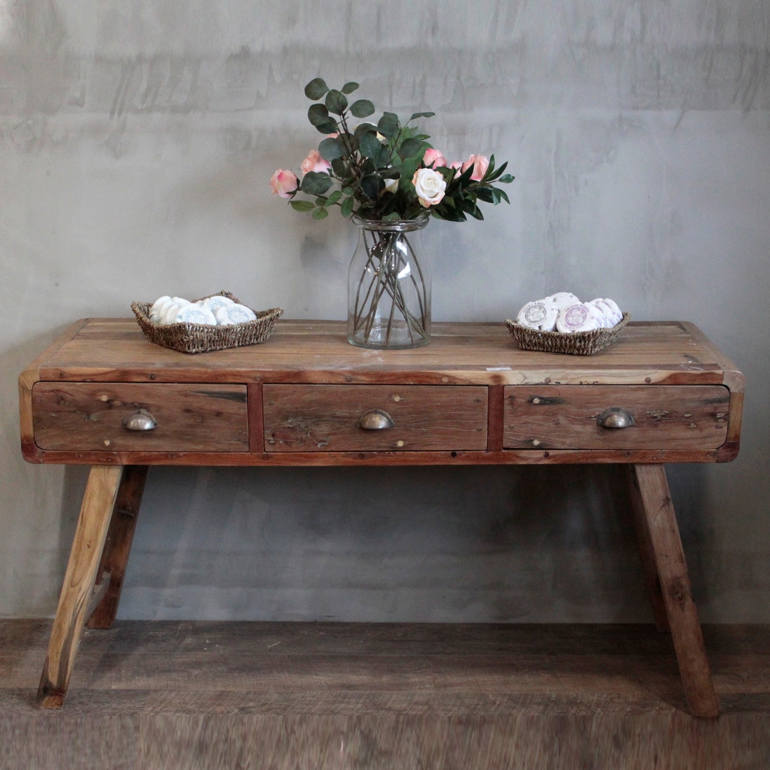 A recycled wood console table with a vase of flowers.