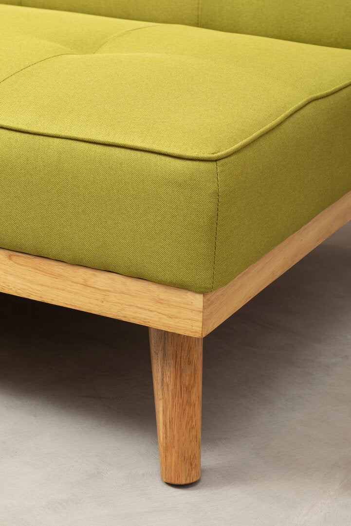 Close up of a lime green fabric sofa bed with wooden legs on a neutral floor