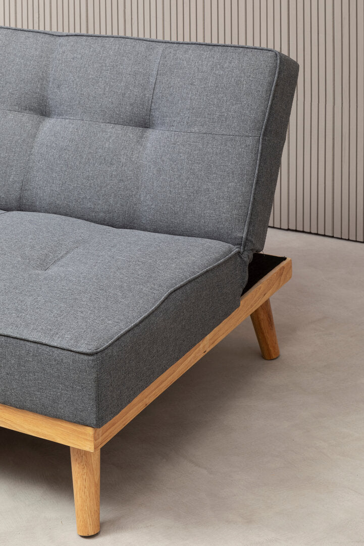 Gray fabric sofa bed with wooden legs on a neutral background