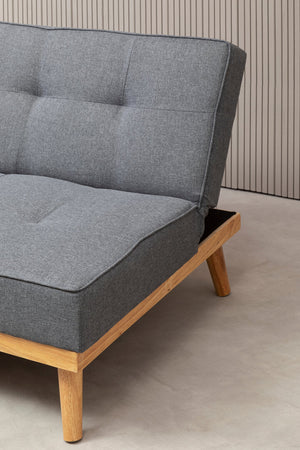 Gray fabric sofa bed with wooden legs on a neutral background