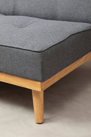Gray upholstered sofa with wooden legs on a neutral background