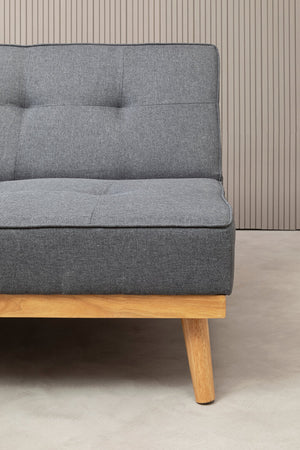 Gray fabric sofa with wooden legs against a neutral wall.