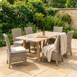 Outdoor Capri patio set with wooden table and wicker chairs on a stone patio.