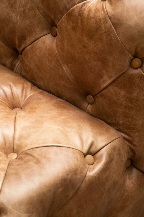 Close-up of a brown leather sofa with buttoned details