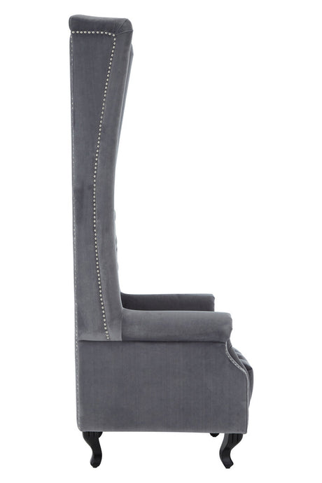 Side view of grey tufted chair with high back and armrests on a white background