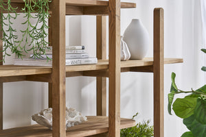 A close up of  rustic open shelving unit with decorative items and books and a plant in the background