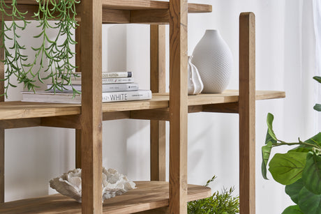 A close up of  rustic open shelving unit with decorative items and books and a plant in the background