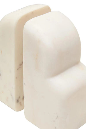 Close-up of the Vela white marble bookends from the side, showing their rounded edges and solid marble depth.
