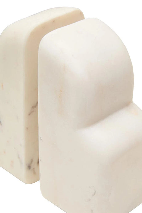 Close-up of the Vela white marble bookends from the side, showing their rounded edges and solid marble depth.