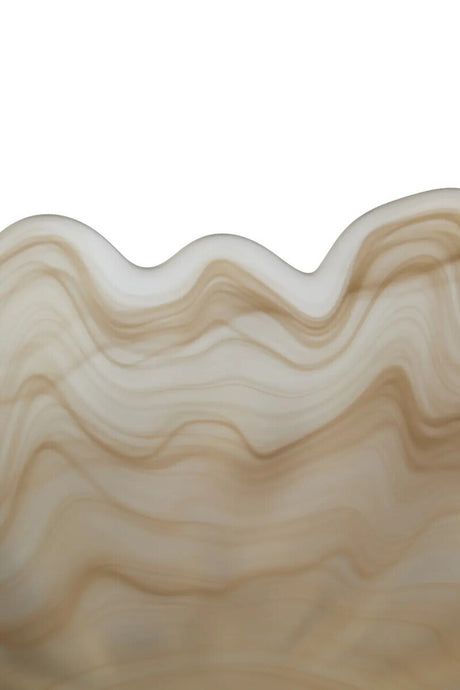 A close-up of a wavy, scalloped edge made from a translucent beige glass with layered tan and cream marbling, set against a plain white background.