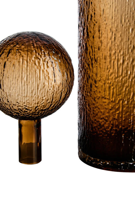 Textured brown glass sphere and cylindrical container on a white background
