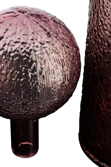 Close-up of a textured pink vase and stopper on a white background