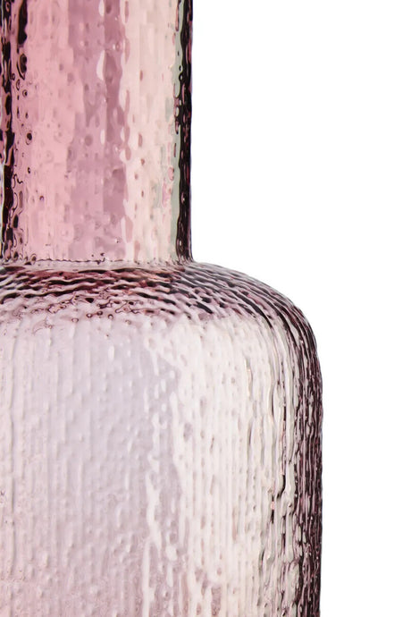 Close-up of a textured pink glass bottle on a white background