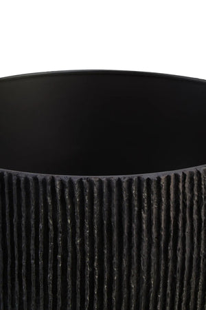 The shade of a black ribbed table lamp on a white background
