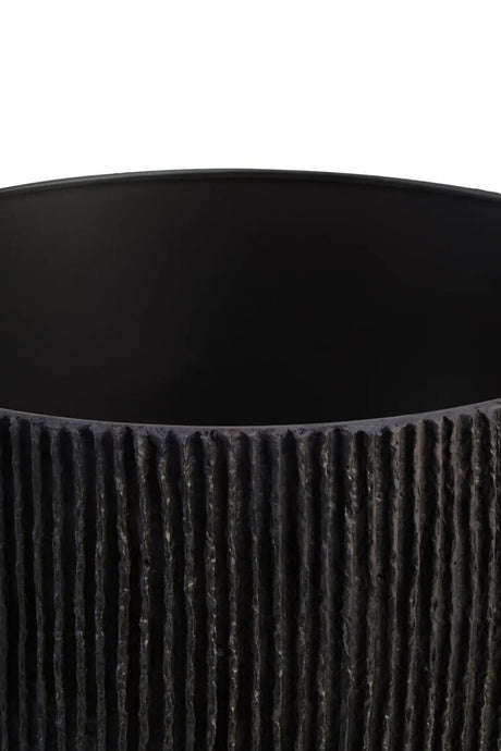 The shade of a black ribbed table lamp on a white background
