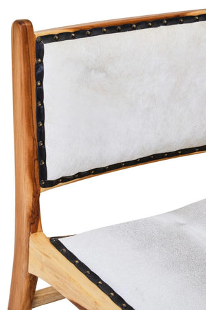 Close-up of the Jakarta Dining Chair back, with cream hair-on cowhide, black leather edging and antique brass studs.
