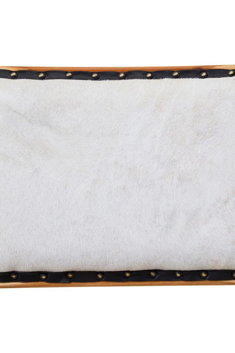 Close-up of the cream hair-on cowhide on the Jakarta Dining Chair, edged in black leather with brass studs.
