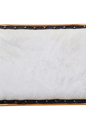 Close-up of the cream hair-on cowhide on the Jakarta Dining Chair, edged in black leather with brass studs.