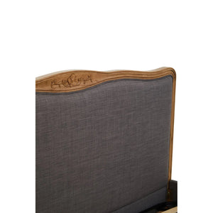 Close view of the Vienne bed headboard, showing the carved oak crest and grey upholstery.